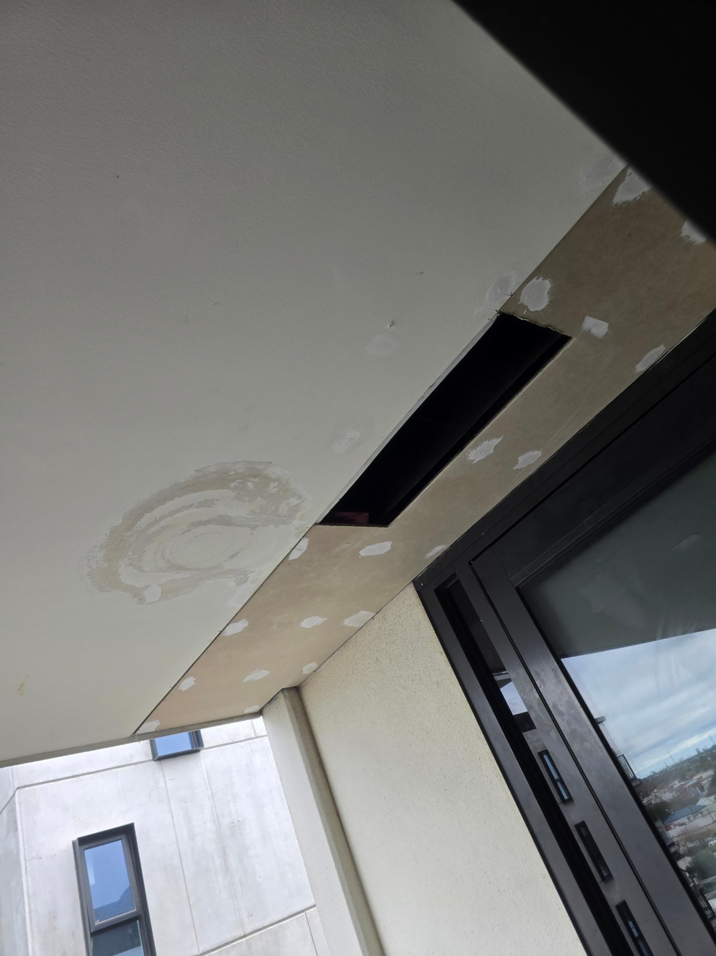 Water damaged fibre cement sheet cut out of the ceiling below a balcony