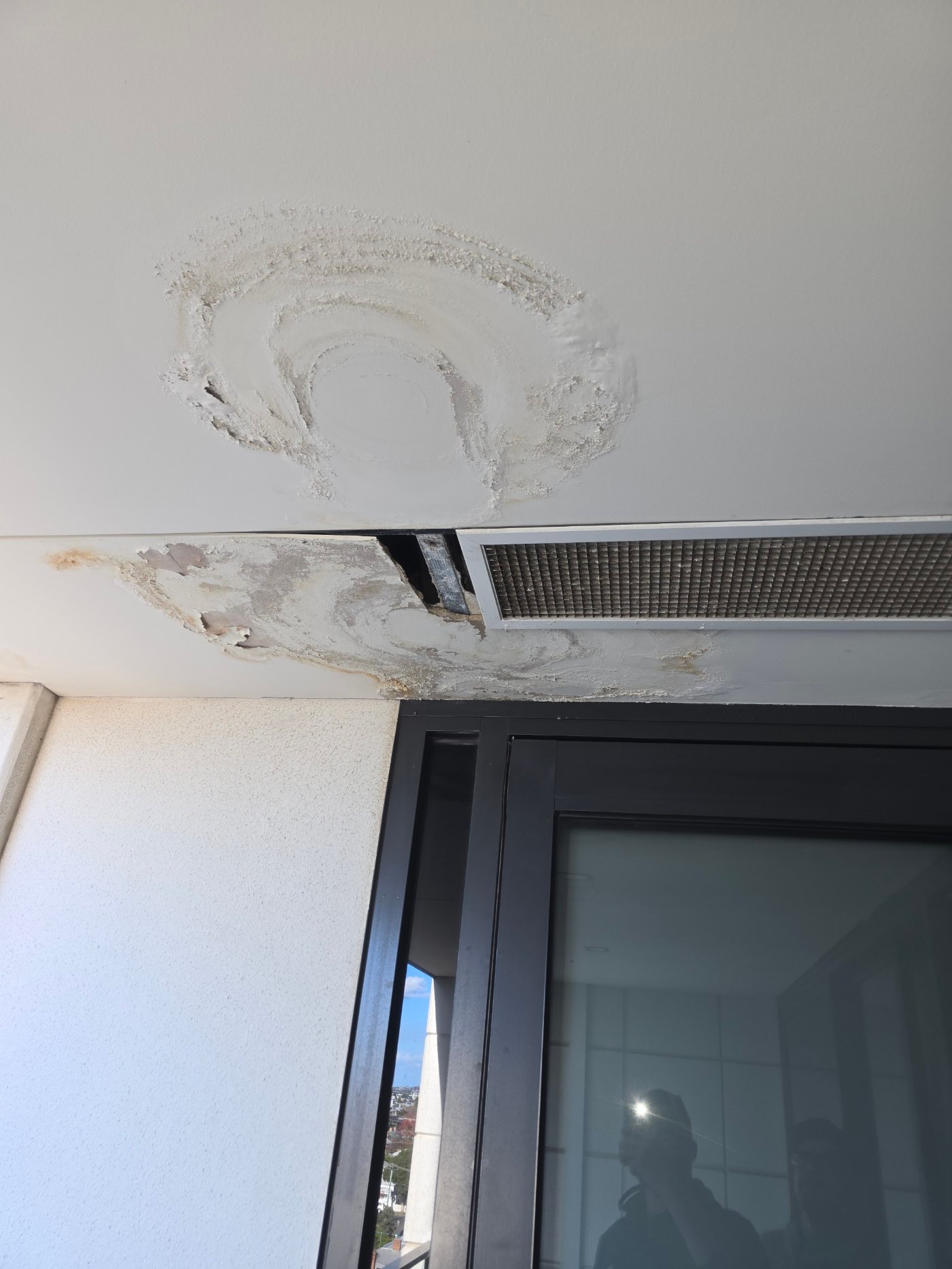 Blistered and stained ceiling in the apartment below a leaking balcony